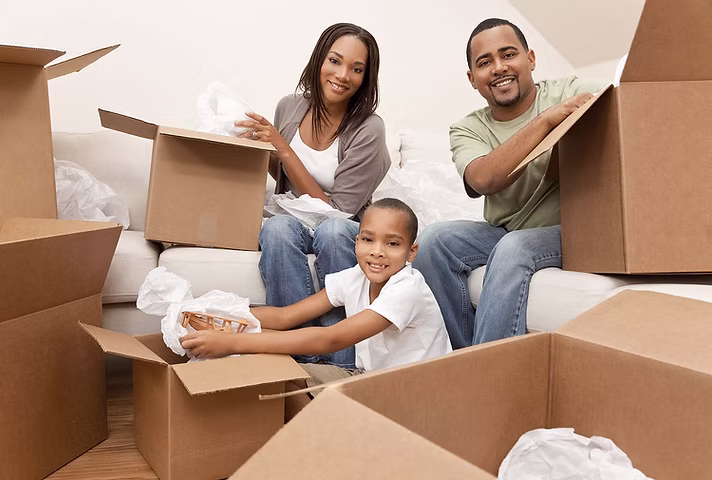 Happy family of four inside new home with moving boxes