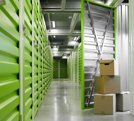 Indoor self-storage units with green doors and stacked boxes